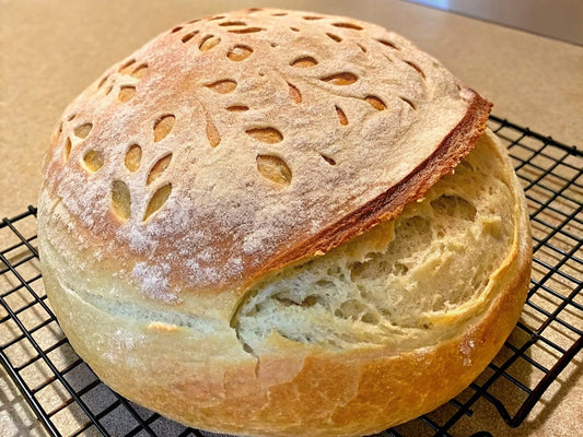 A freshly baked sourdough bread with a golden-brown crust cooling on a wire rack.